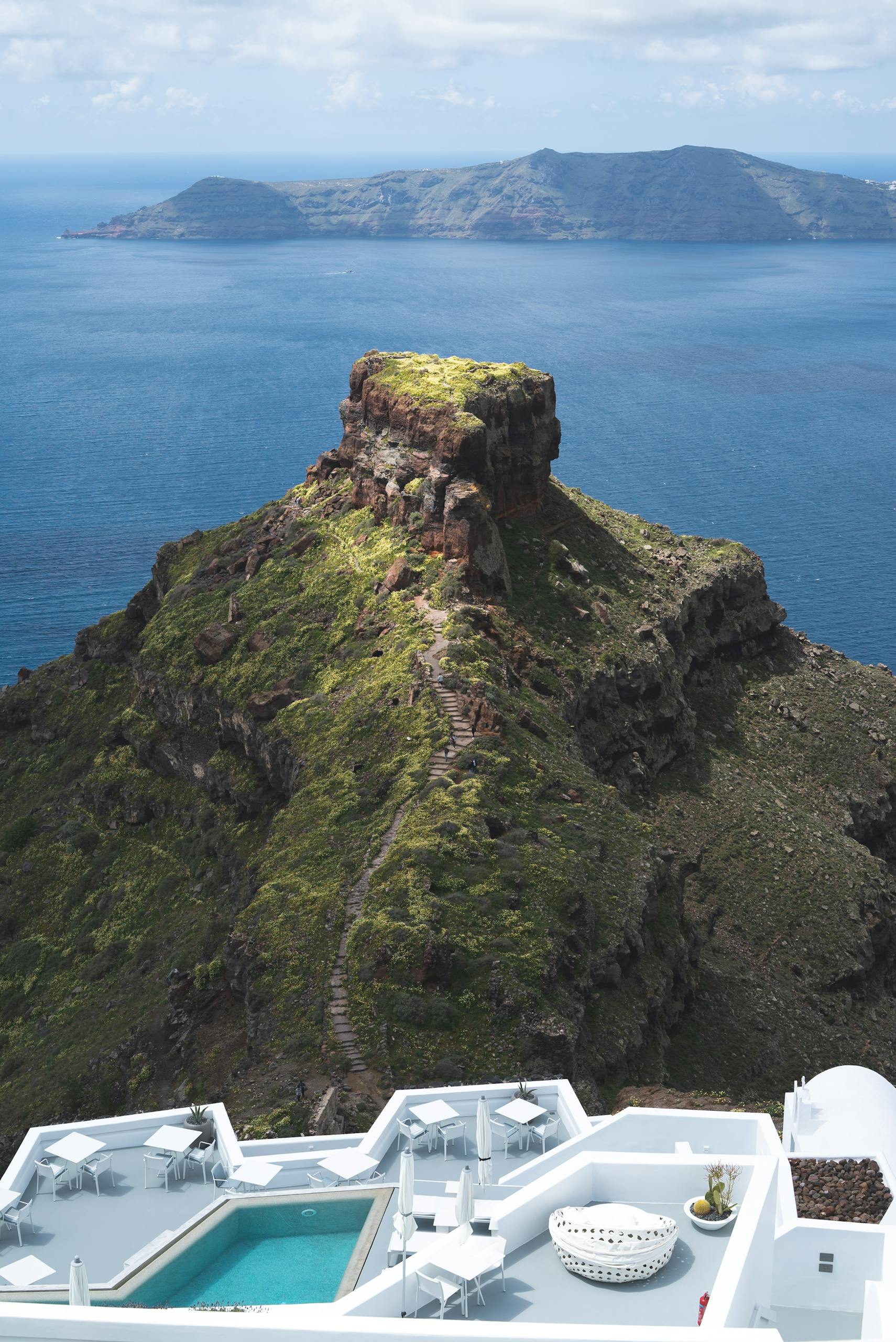 A breathtaking view of Santorini's cliffs and the Aegean Sea with a luxurious poolside setting.