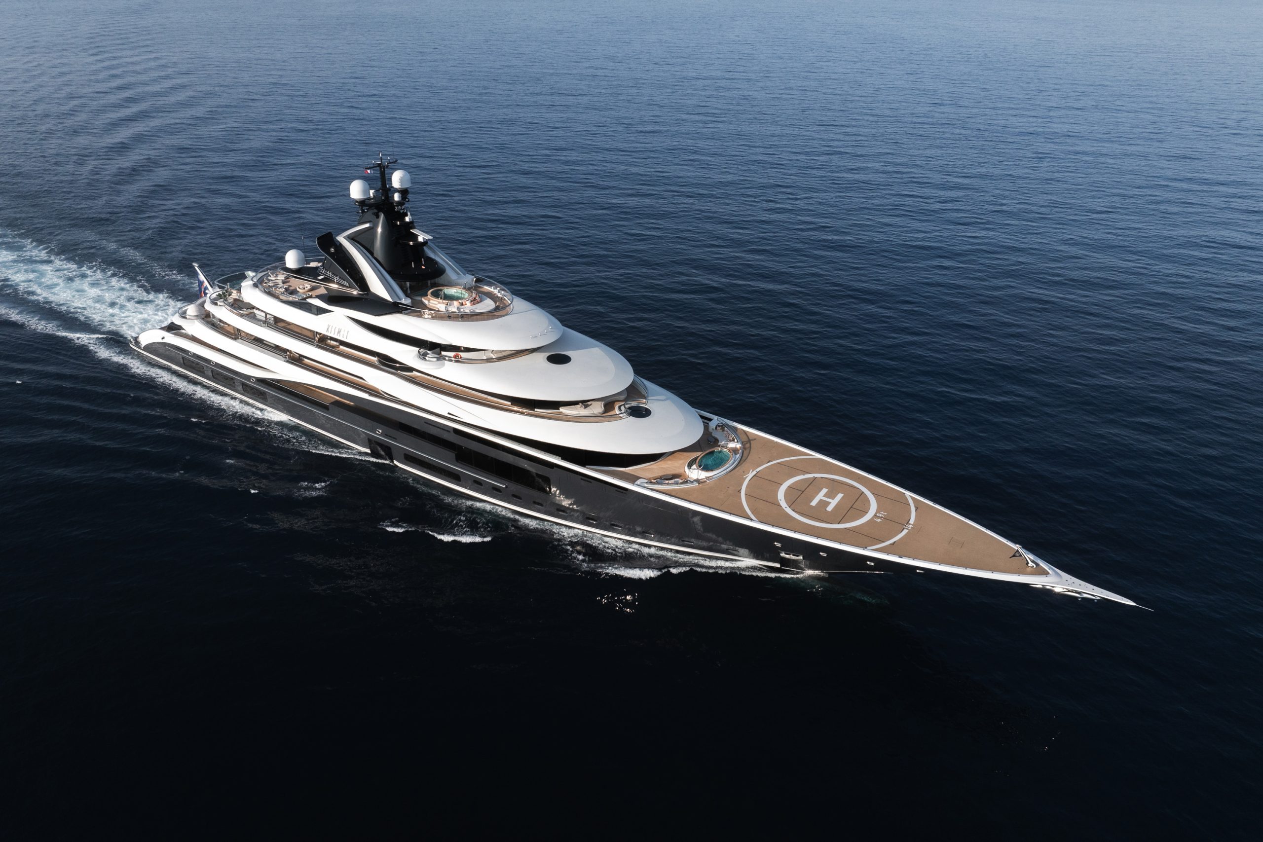 Superyacht Kismet cruising through open water, featuring a helipad, jacuzzis, and a sleek multi-deck design.