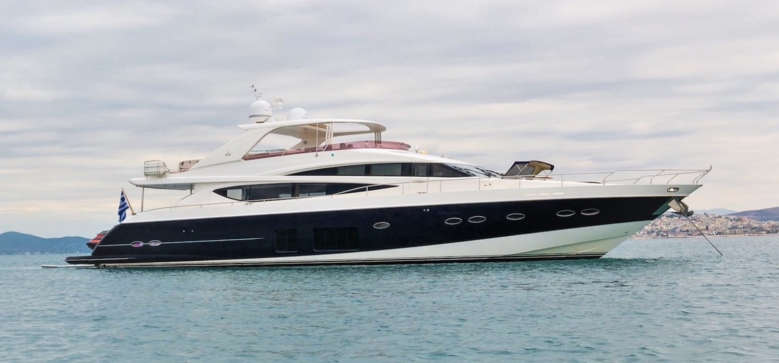 4LIFE luxury motor yacht anchored calmly near the coastline, with a black and white hull and spacious flybridge.
