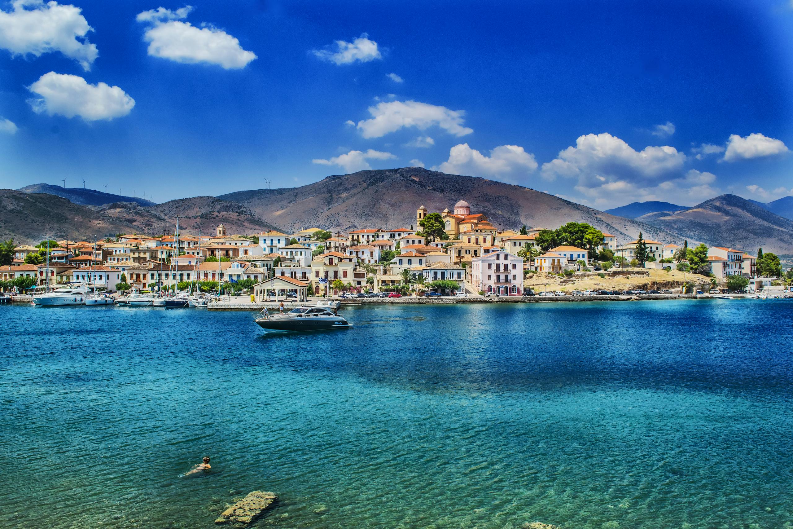 A charming Greek coastal town against a mountainous backdrop.